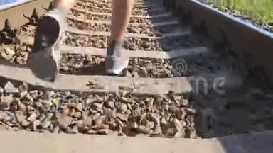 男足在铁轨上的铁轨之间奔跑。 在铁路枕木上慢跑的跑步者。 运动腿